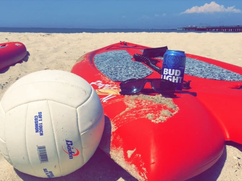 A volleyball and paddleboards on the sand at the beach